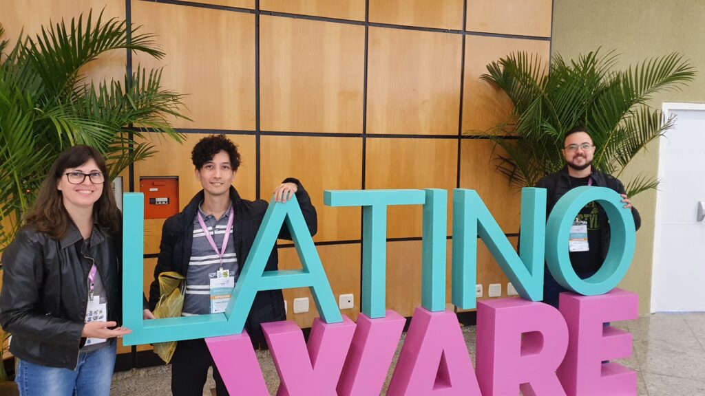 Members of the KDE Brasil Network pose behind a LatinoWare sign.